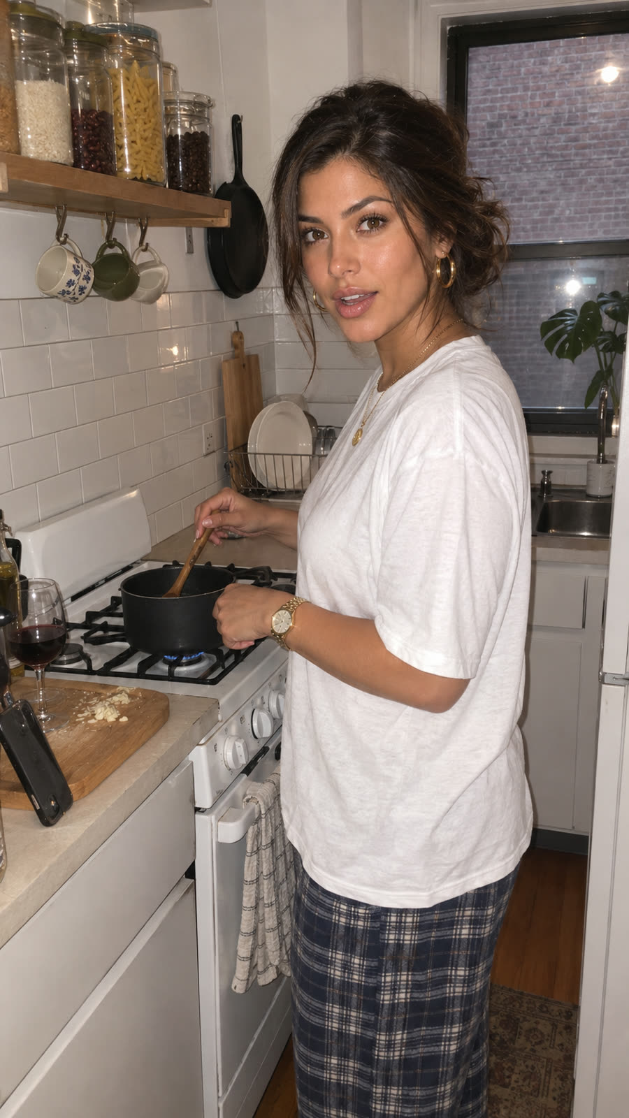 AI-generated image of Linda: in a small white galley kitchen, white tee and plaid pants, stirring a pot on the stove, a glass of red wine on the counter
